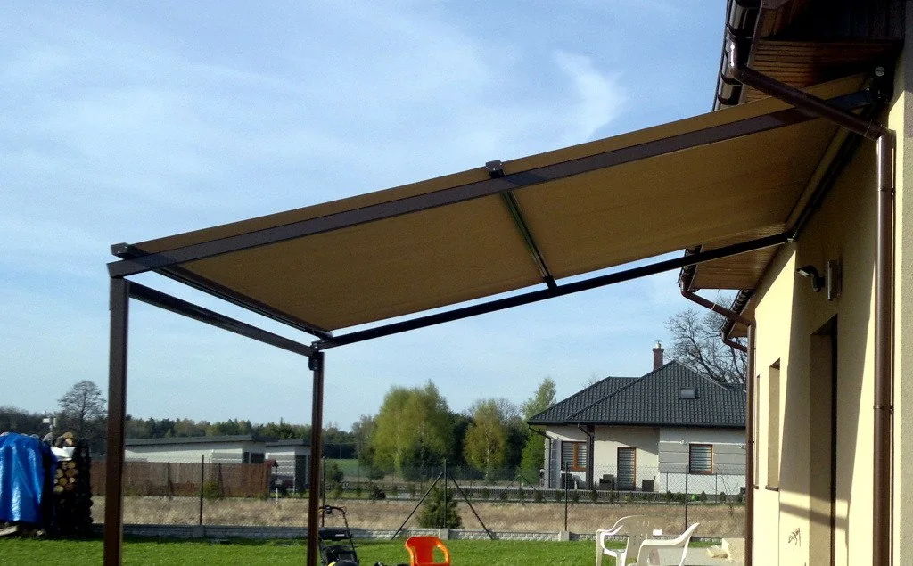 Pergola med mørke profiler og takduk ved en bolig