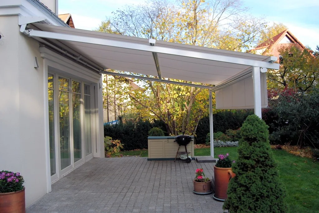 Hvit pergola med tak over en sittegruppe på terrassen